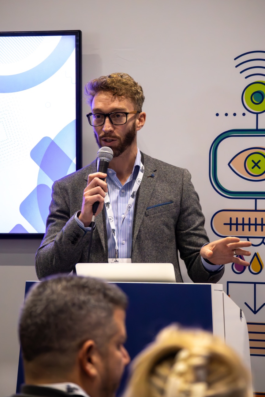 Luke Quilter presenting with a microphone at a conference